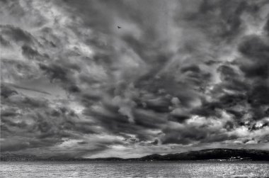 Çok dramatik bir gökyüzü ve denizin üzerinde uçan bir kuş.