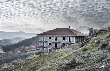 Valtesiniko adındaki dağ köyündeki bulutlu gökyüzünün altındaki taş binanın manzarası. Arkadya- Yunanistan