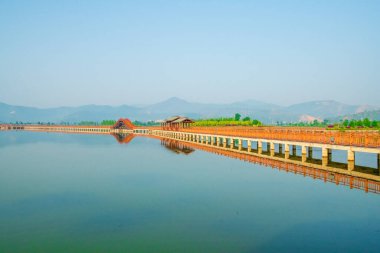 Gölün etrafında yürüyor ve manzarayı seyrediyor.