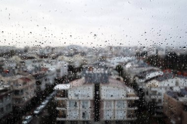 Blurred city view from behind glass with raindrops