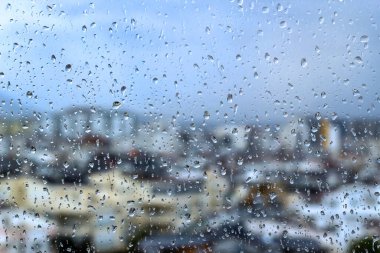 Blurred city view from behind glass with raindrops