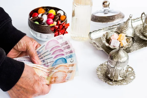 トルコの銀行券は コロン カラフルなキャンディー トルコのコーヒーセットで白い上の高齢者の手の中にあります ロイヤリティフリーのストック写真