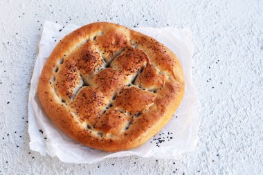 Geleneksel Türk Ramazan Ekmeği, beyaz desenli arka plan üzerine fırın kağıdı, yukarıda görünüm