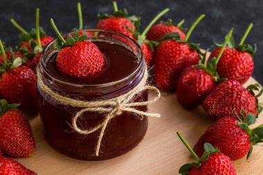 Doğal çilek reçeli ve siyah yüzeyde olgun çilekler.