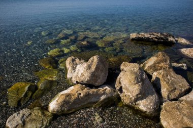 Büyük dekoratif taşları olan mavi, temiz bir sahil.