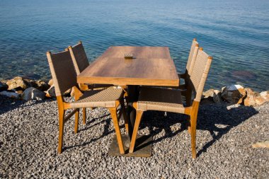 Mavi denizin yanında dört sandalyeli boş bir masa.