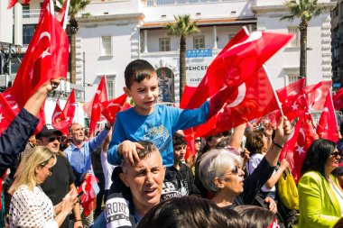 İzmir, Konak, Türkiye 30.04.2023 Mavi tişörtlü siyah saçlı bir Türk çocuk, babasının omzunda oturuyor, Türk bayrağını kalabalıkla sallıyor