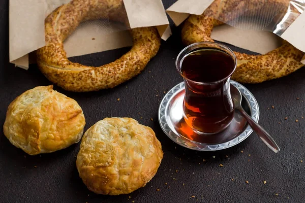 土耳其传统的糕点糕点产品 各种带有芝麻面包圈 筛子和土耳其茶的黑色表面与牛皮纸袋 — 图库照片