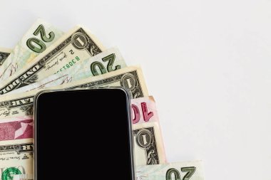 Beyaz yüzey üzerinde bir dolarlık banknotlarla Türk para tasarımı ve boş siyah ekranlı akıllı telefon