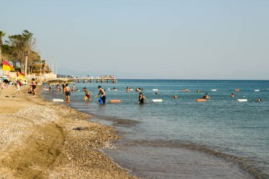 İzmir, Gumuldur, Türkiye 06.23.2023 Çocuklar, gençler ve kadınlar, sarı ve kırmızı bayrak uyarısına rağmen yaz mevsiminde denizde yüzüyor