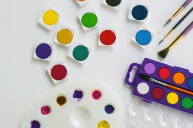 Beyaz yüzeyde boya fırçası olan renkli suluboya. Eğitim konsepti.