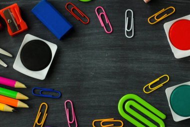 Renkli okul, tebeşirli siyah arkaplan üzerine suluboya boya seti, boya kalemleri ve kalemler sağlar. Eğitim kavramı.