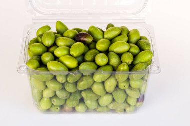 Beyaz yüzeydeki plastik kutuda taze toplanmış yeşil doğal zeytinler.