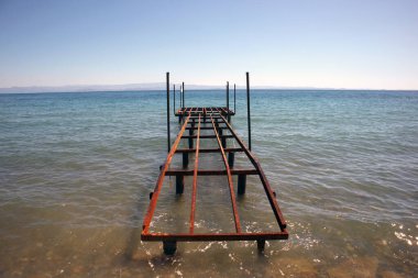 Ahşap yürüyüş yolu mavi denizde paslı iskeleyi söktü.