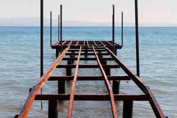 Ahşap yürüyüş yolu mavi denizde paslı iskeleyi söktü.