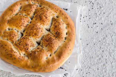 Geleneksel Türk Ramazan Ekmeği, beyaz desenli arka plan üzerine fırın kağıdı, yukarıda görünüm