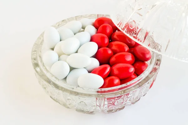 Red and white candied almonds designed half and half in a crystal candy bowl