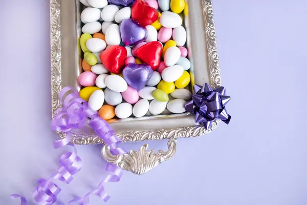 カラフルなアーモンドキャンディーは ハート型のチョコレートで銀製のトレイにデザインされました ストック画像