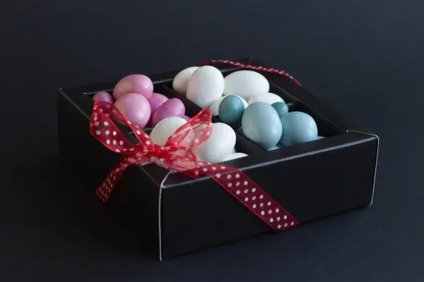 传统的 白色的 淡淡的色调是彩色的 巧克力包裹着杏仁糖果 黑盒上有红丝带 免版税图库照片