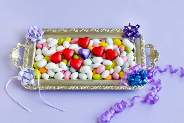 在装有心形巧克力的银盘上设计了色彩艳丽的杏仁糖果 免版税图库图片