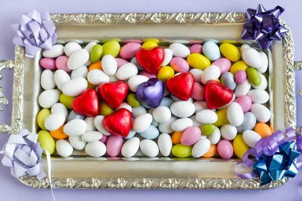 在装有心形巧克力的银盘上设计了色彩艳丽的杏仁糖果 免版税图库图片