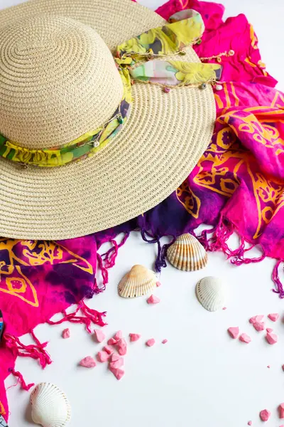 白い表面にマッスル貝とビーチショールで設計された広いレンズの女性のわら帽子 ストック画像