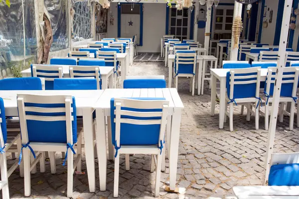 Boş, mavi yastıklı beyaz masalar bir balık lokantasında, yakın plan çekilmiş.