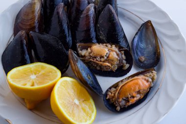 Geleneksel Türk midyeleri beyaz porselen tabakta taze, dilimlenmiş limonla