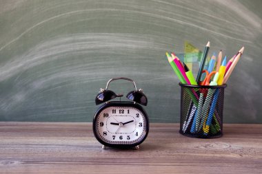 Siyah renk, yeşil karatahtanın önündeki metal alarm saati kalem tutacağı. Eğitim kavramı.