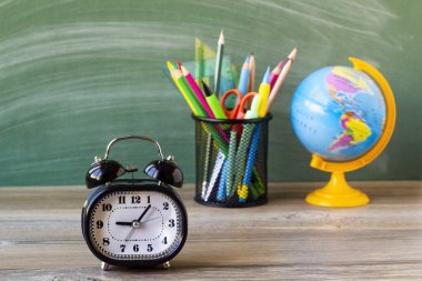 Siyah renk, yeşil yazı tahtasının önündeki metal alarm saati kalem tutacağı ve küresi. Eğitim kavramı.