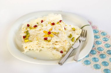 Geleneksel Türk Ramazan Tatlısı bir porsiyon çatal bıçak ve mavi dantelli Gullac