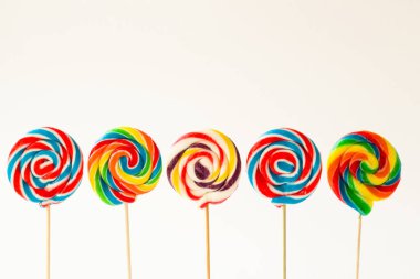 Beyaz yüzeyde renkli çubuk, spiral lolipop şekerler kopyalama alanı ile ayakta duruyor