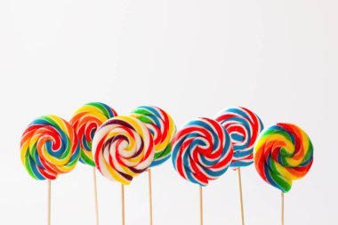 Beyaz yüzeyde renkli çubuk, spiral lolipop şekerler kopyalama alanı ile ayakta duruyor