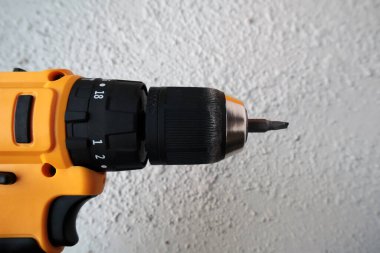 Küçük sarı bir çekiç matkabı duvarın önünde duruyor.