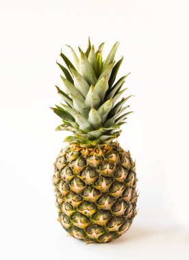 Beyaz yüzeyde duran yeşil yapraklı bir ananas.