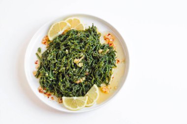 Beyaz bir tabakta dilimlenmiş limonla servis edilen haşlanmış deniz fasulyesi.