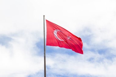 Şehitlerin mezarlığında bayrak direğine çekilen kumaş Türk bayrağı rüzgarda sallanıyordu