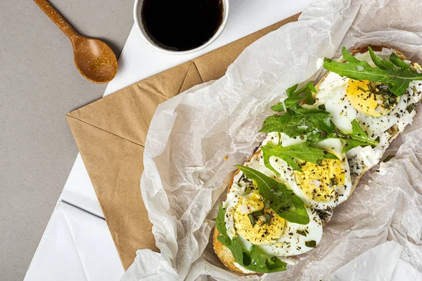 stock image Toast with cream cheese, arugula salad and boiled egg in a recyclable paper bag from above. Take away concept