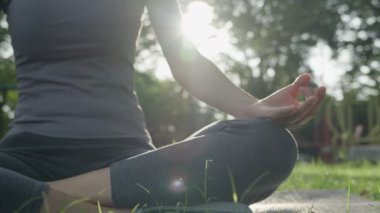 Kadın parkta meditasyon yapıyor. Sabahları egzersiz yapan Asyalı bir kadın. denge, dinlenme, rahatlama, sakinlik, sağlık, mutluluk, rahatlama, sağlıklı yaşam tarzı, stresi azaltma, huzur, tutum.