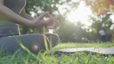 Kadın parkta meditasyon yapıyor. Sabahları egzersiz yapan Asyalı bir kadın. denge, dinlenme, rahatlama, sakinlik, sağlık, mutluluk, rahatlama, sağlıklı yaşam tarzı, stresi azaltma, huzur, tutum.