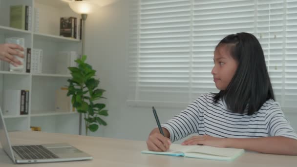 亚洲小女孩在家里学习 和慈祥的妈妈一起做作业 鼓励她考试 妈妈把一杯牛奶传给女儿 女孩快乐的家庭学校 妈妈一起教和建议教育 — 图库视频影像
