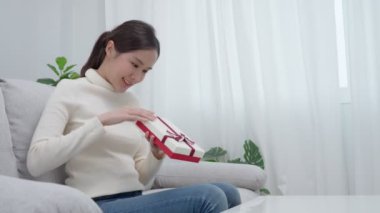 Güzel Asyalı kadın şaşırır ve hediye kutusuyla ilgilenir. Sevimli kız hediye kutusunu açtı. Doğum günü, kutlama, xmas, yeni yıl festivali, teşekkür, kutlama, sevgililer günü, yıldönümü