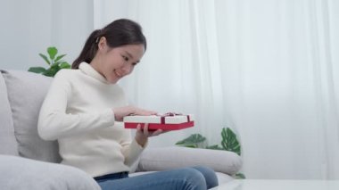 Güzel Asyalı kadın şaşırır ve hediye kutusuyla ilgilenir. Sevimli kız hediye kutusunu açtı. Doğum günü, kutlama, xmas, yeni yıl festivali, teşekkür, kutlama, sevgililer günü, yıldönümü
