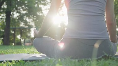 Kadın parkta meditasyon yapıyor. Sabahları egzersiz yapan Asyalı bir kadın. denge, dinlenme, rahatlama, sakinlik, sağlık, mutluluk, rahatlama, sağlıklı yaşam tarzı, stresi azaltma, huzur, tutum.