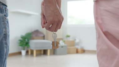 Moving house, relocation. Couple hold key house keychain in new apartment, inside the room was a cardboard box containing personal belongings and furniture. move in the new apartment or condominium