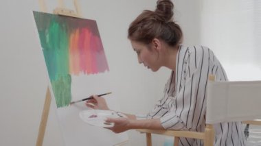 Profesyonel kadın sanatçı kız, sanat eseri yaratmak için soyut sanatlarda boya fırçası kullanır. Stüdyoda suluboya ya da yağlı boya boya. Güzel bir kadın resim yapmaktan zevk alır. iş eğlencesi