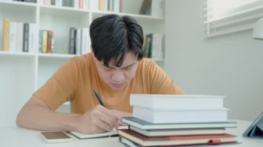 Asyalı öğrenci sınavlar yüzünden endişeli. Erkek öğrenci kütüphanede sınav ve öğrenme derslerine hazırlanıyor. Stres, umutsuzluk, acele, yanlış anlama okuma, cesaret kaybı, beklenti, bilgi, yorgunluk