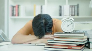 Asyalı öğrenci sınavlar yüzünden endişeli. Erkek öğrenci kütüphanede sınav ve öğrenme derslerine hazırlanıyor. Stres, umutsuzluk, acele, yanlış anlama okuma, cesaret kaybı, beklenti, bilgi, yorgunluk