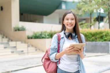 Beautiful student asian woman with backpack and books outdoor. Smile girl happy carrying a lot of book in college campus. Portrait female on international Asia University. Education, study, schoo