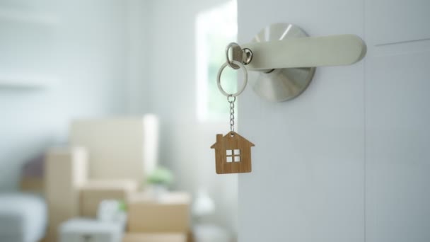 钥匙插在新房子的门上 房间里有一个装有个人物品和家具的纸板箱 搬进公寓或公寓 — 图库视频影像